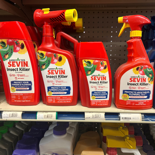 Four red bottles of Sevin Insect Killer with yellow nozzles are displayed on a store shelf, each labeled for protecting gardens and flowers.