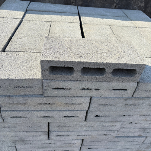 Stacked gray concrete blocks with a textured surface and rectangular holes are neatly arranged. The scene conveys an industrial, sturdy feel.