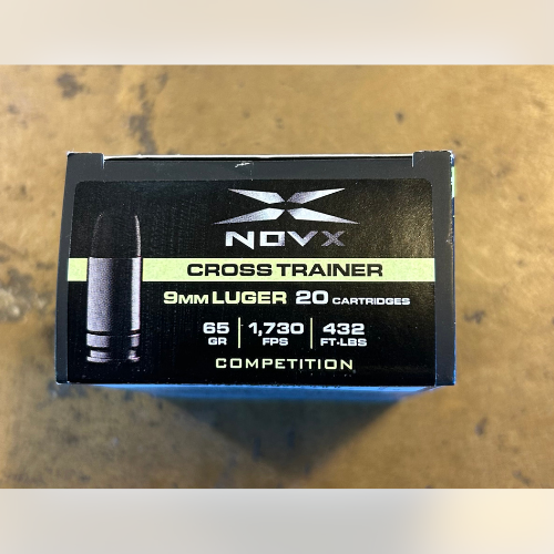 Box of NovX Cross Trainer 9mm Luger cartridges on a wooden surface. Black and green design includes details: 65 GR, 1,730 FPS, 432 FT-LBS, 20 cartridges.