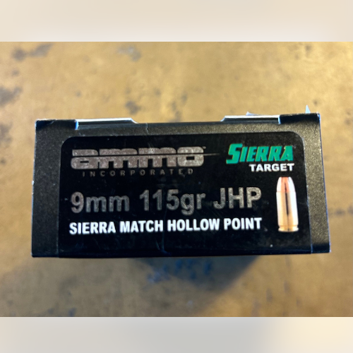 Box of 9mm 115gr JHP ammunition, Sierra Match Hollow Point, on a wooden surface. Black packaging with clear, bold text and bullet graphic.