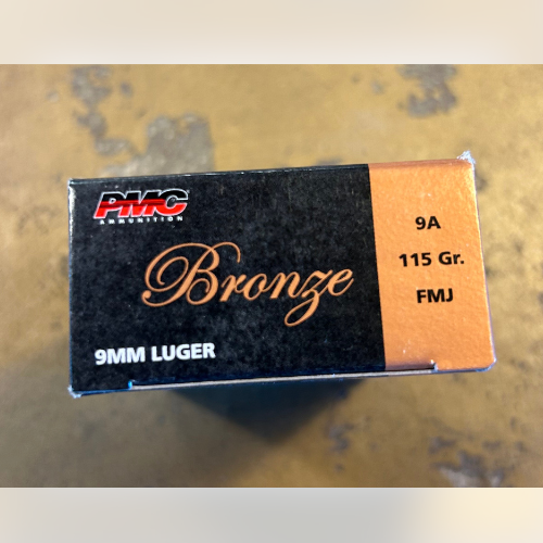 A box of PMC bronze 9mm Luger ammunition is shown, featuring black and bronze colors with 