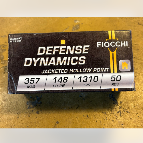 Box of Fiocchi Defense Dynamics .357 Magnum ammo, jacketed hollow point, 148 grain, 1310 FPS, 50 rounds. Black and yellow design on wooden table.