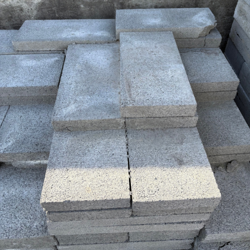 Stacked grey concrete blocks arranged uniformly on a construction site. The rough texture and even alignment convey organization and stability.