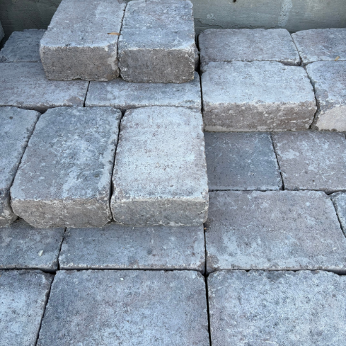 Rough, weathered gray stone blocks form uneven steps, creating a rustic, textured surface. The arrangement conveys an aged, natural charm.