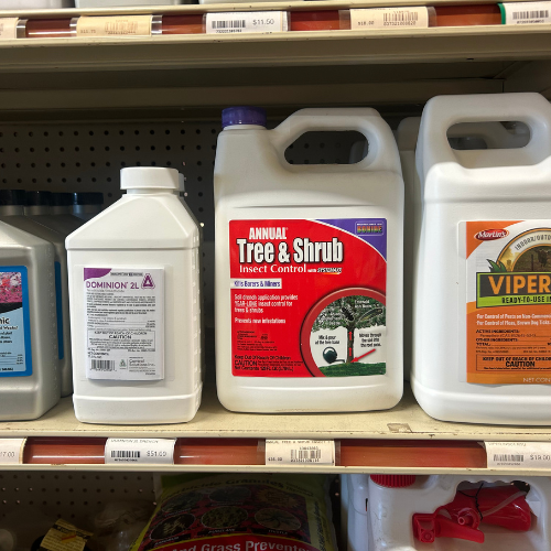 Bottles of insect control products on a store shelf. The central bottle is labeled 