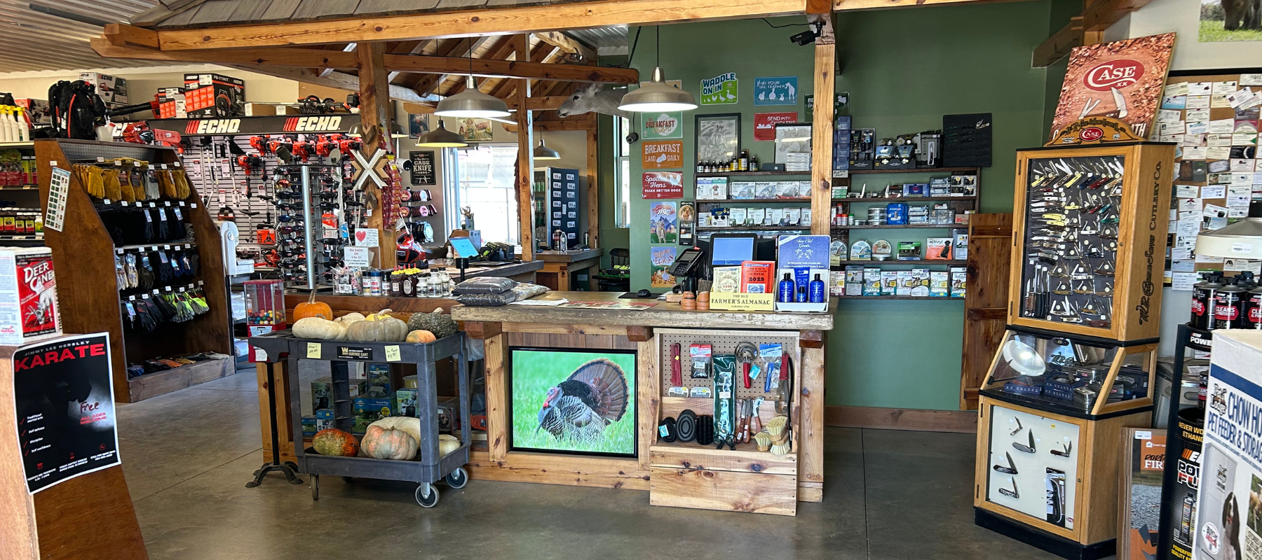 Cozy store interior with wooden counter, displaying various tools and outdoor gear. Shelves filled with merchandise, and a cart with pumpkins. Warm, inviting ambiance.